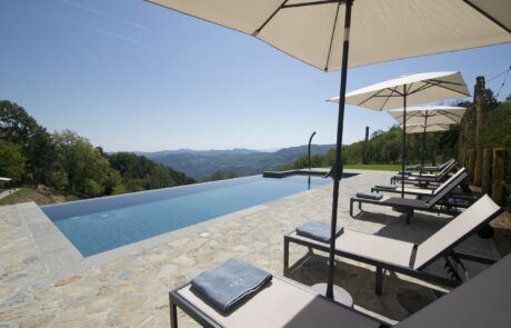Piscina a sfioro con lettini e vista panoramica sulle colline dell'Alta Langa in Piemonte