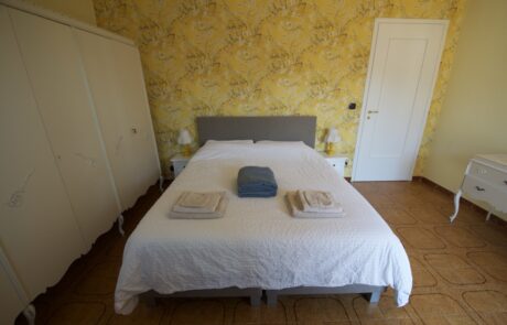 Letto matrimoniale in una camera da letto di La Cascina con una parete d'accento in un caldo giallo
